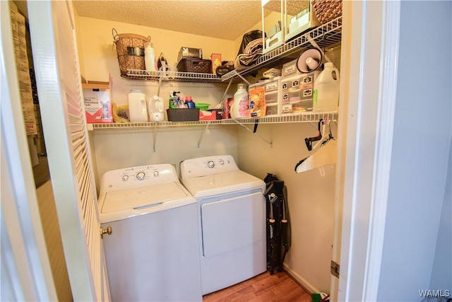 washroom with hardwood / wood-style floors, a textured ceiling, and washing machine and clothes dryer