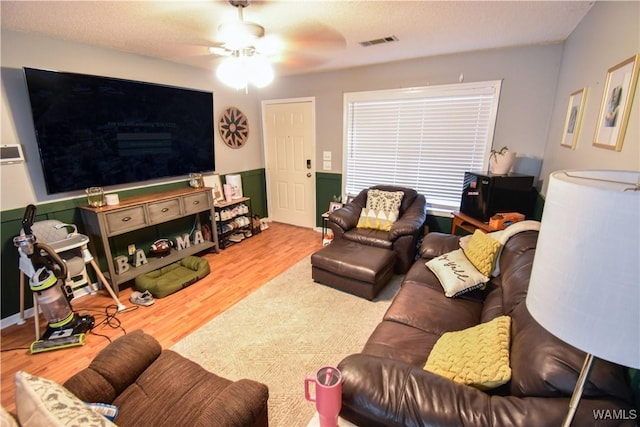 living room featuring hardwood / wood-style floors, ceiling fan, and a textured ceiling