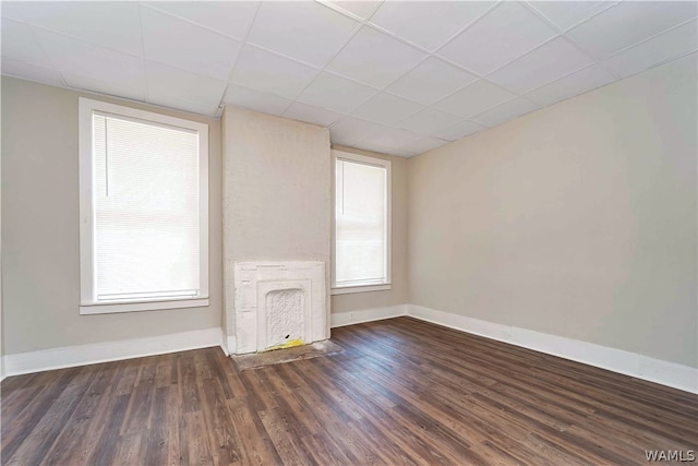 unfurnished living room with dark hardwood / wood-style floors and a drop ceiling