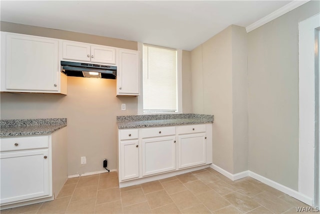 kitchen with light tile patterned floors, white cabinetry, crown molding, and light stone counters