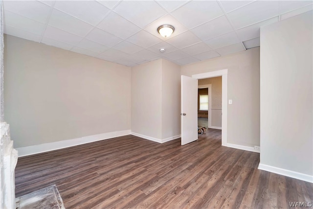 empty room with a paneled ceiling and dark wood-type flooring