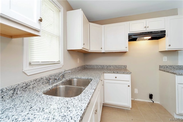 kitchen with white cabinetry, sink, and light stone countertops