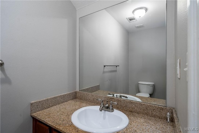 bathroom featuring visible vents, toilet, and vanity