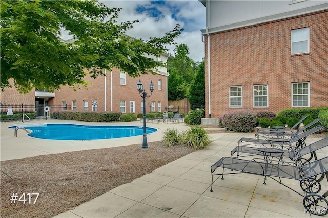 community pool with a patio area and fence