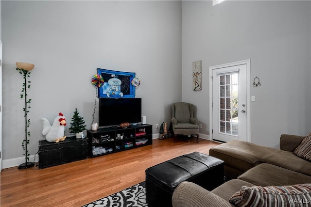 living room featuring wood finished floors, baseboards, and a towering ceiling