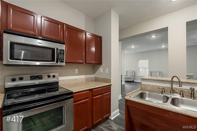 kitchen featuring a sink, appliances with stainless steel finishes, dark wood-style floors, and light countertops