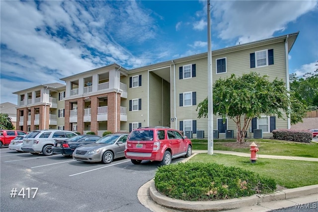 view of building exterior featuring uncovered parking and central AC