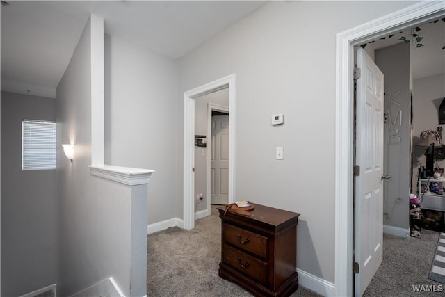 hall featuring an upstairs landing, baseboards, and carpet