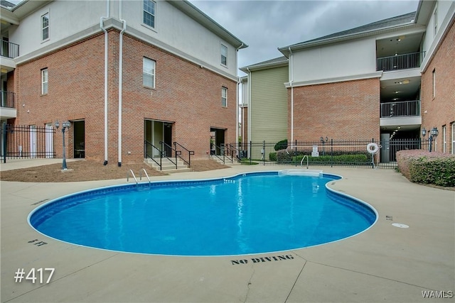 community pool featuring a patio, entry steps, and fence