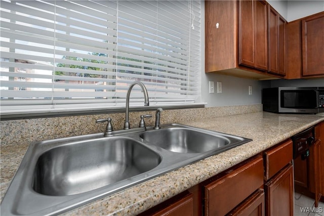 kitchen with a sink, stainless steel microwave, dishwashing machine, and light countertops