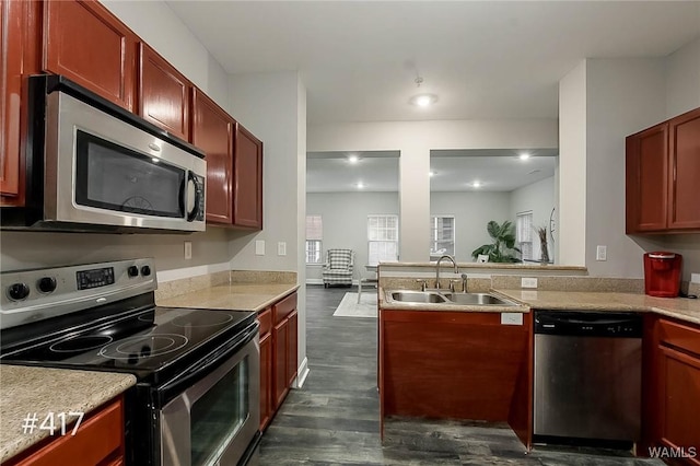 kitchen featuring a sink, dark wood-style floors, stainless steel appliances, reddish brown cabinets, and light countertops