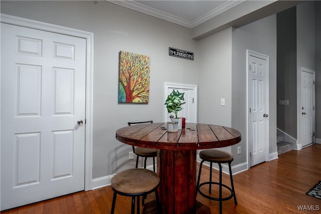 dining space with crown molding, baseboards, and dark wood-style flooring