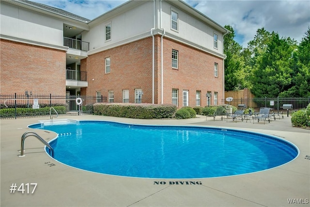 community pool with a patio area and fence