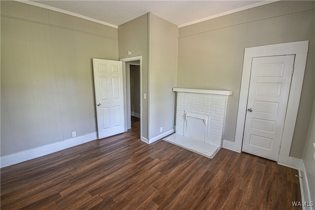 unfurnished living room featuring a brick fireplace, dark wood-type flooring, and ornamental molding