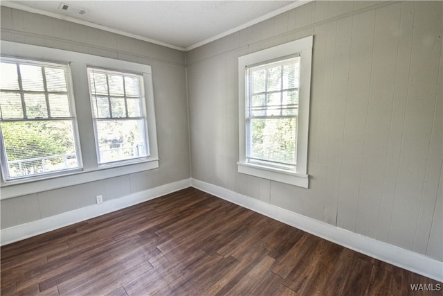 spare room featuring crown molding, wooden walls, and dark hardwood / wood-style floors