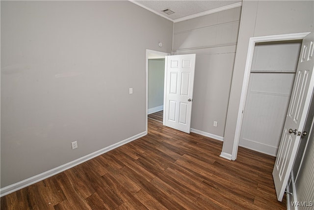 unfurnished bedroom with dark hardwood / wood-style floors, a closet, and crown molding