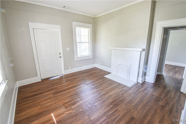 spare room with crown molding, dark hardwood / wood-style floors, and a brick fireplace