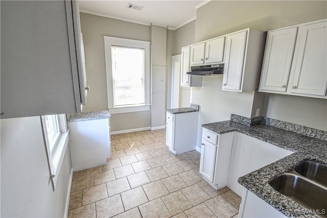 kitchen featuring dark stone countertops, white cabinetry, and ornamental molding