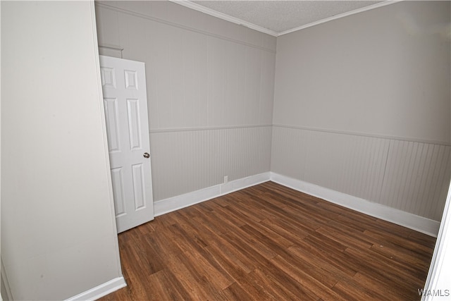 empty room with a textured ceiling, wood walls, dark hardwood / wood-style floors, and ornamental molding