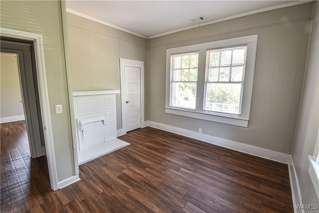 unfurnished living room featuring a textured ceiling, dark hardwood / wood-style flooring, a brick fireplace, and ornamental molding