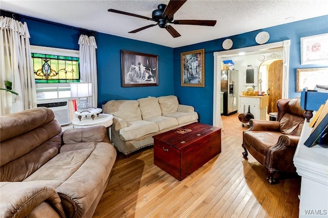 living room with ceiling fan, cooling unit, a textured ceiling, a healthy amount of sunlight, and light wood-style floors