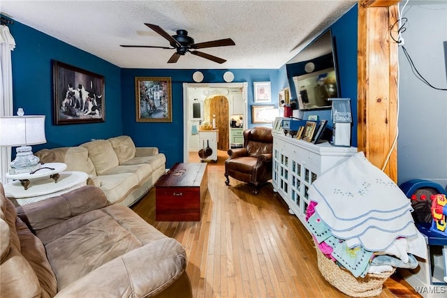 living area with ceiling fan, a textured ceiling, and light wood finished floors