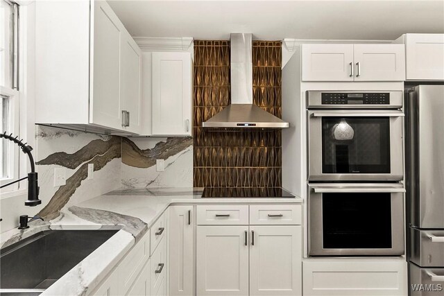 600 Innsbruck Ct, Northport, AL 35473 - kitchen with wall chimney exhaust hood, appliances with stainless steel finishes, decorative backsplash, white cabinets, and light stone counters