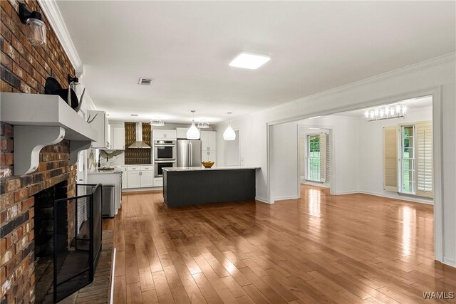 600 Innsbruck Ct, Northport, AL 35473 - unfurnished living room featuring a brick fireplace, ornamental molding, and hardwood / wood-style flooring
