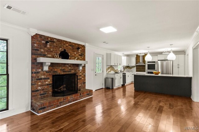 600 Innsbruck Ct, Northport, AL 35473 - unfurnished living room featuring dark wood-type flooring, ornamental molding, and a fireplace