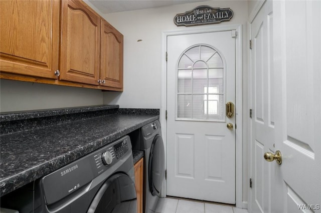 laundry area featuring washing machine and dryer, light tile patterned floors, and cabinets