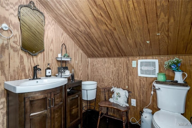 bathroom featuring vanity, toilet, lofted ceiling, and wood walls