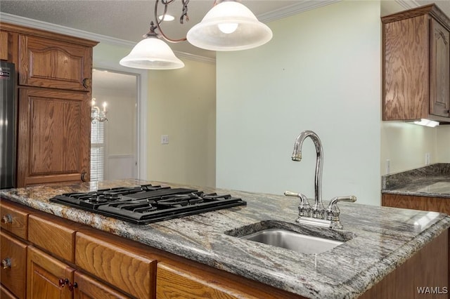 kitchen featuring sink, black gas cooktop, dark stone counters, decorative light fixtures, and ornamental molding