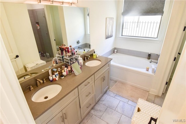 bathroom with double vanity, tile patterned flooring, a sink, and a bath