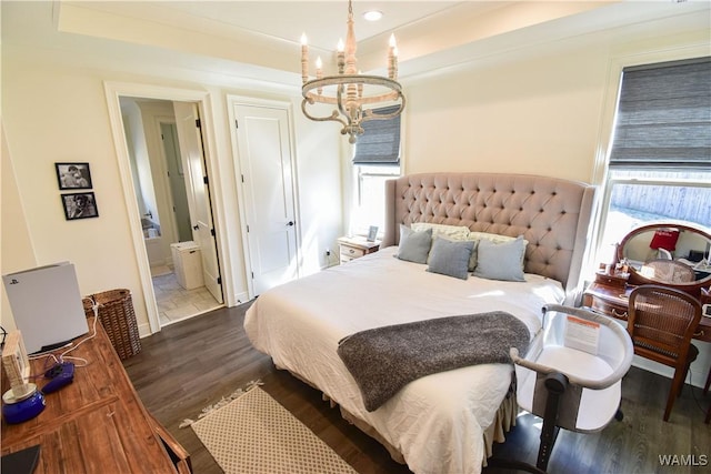 bedroom featuring ensuite bath, a chandelier, and wood finished floors