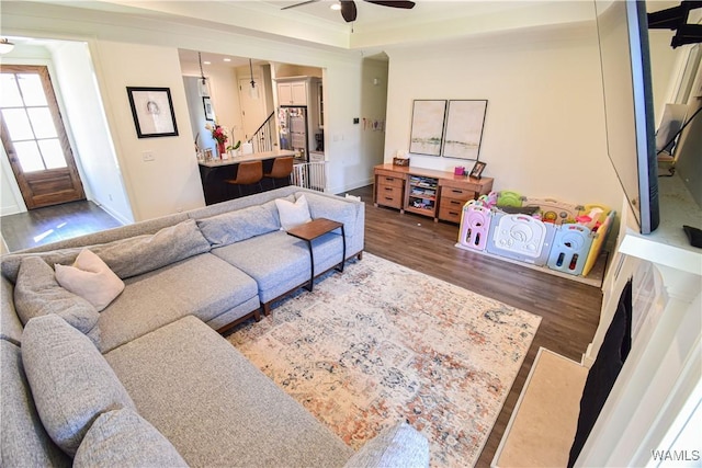 living room with a ceiling fan, a tray ceiling, baseboards, and wood finished floors