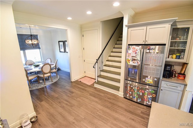 interior space featuring recessed lighting, stainless steel fridge with ice dispenser, white cabinetry, wood finished floors, and baseboards