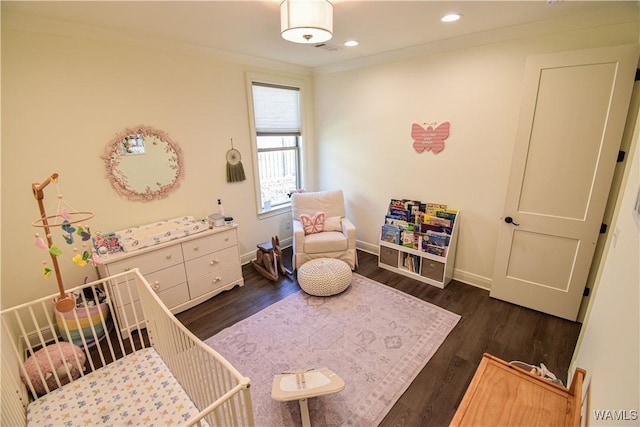 bedroom featuring dark wood-style floors, recessed lighting, a crib, and baseboards