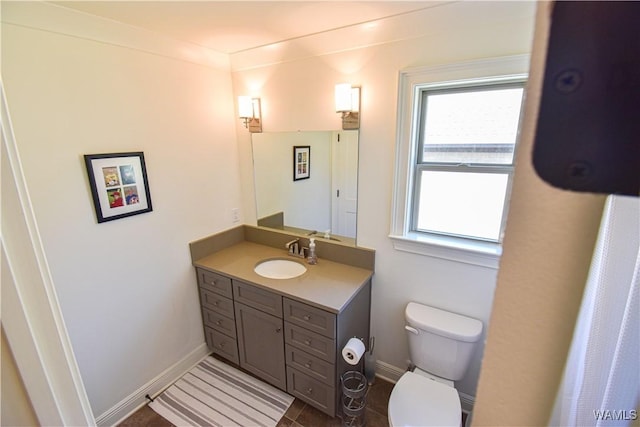 bathroom featuring baseboards, vanity, and toilet