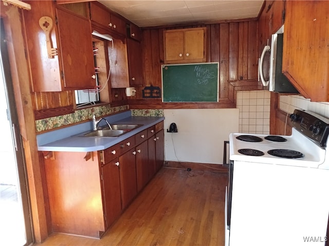 kitchen with decorative backsplash, white electric range, sink, and light hardwood / wood-style flooring