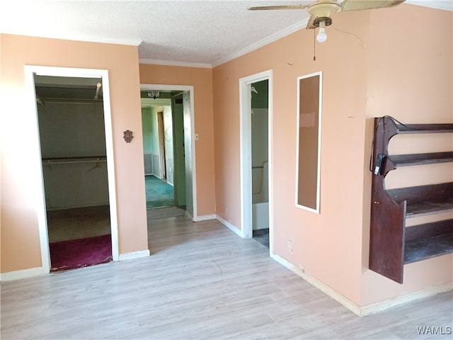 corridor with crown molding, light hardwood / wood-style flooring, and a textured ceiling