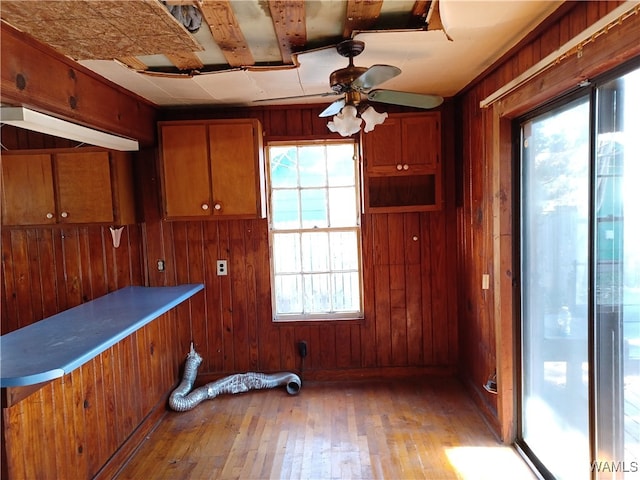 interior space featuring light hardwood / wood-style flooring, a wealth of natural light, wooden walls, and ceiling fan