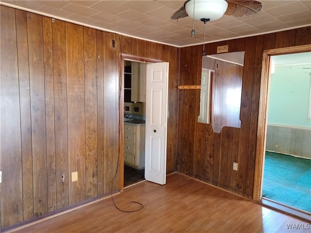 unfurnished bedroom with hardwood / wood-style floors, ceiling fan, and wooden walls