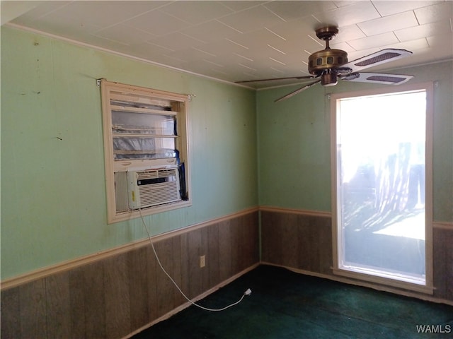 unfurnished room with crown molding, cooling unit, wooden walls, and ceiling fan