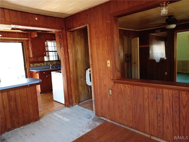 kitchen featuring ceiling fan, washer / dryer, wooden walls, and light hardwood / wood-style flooring