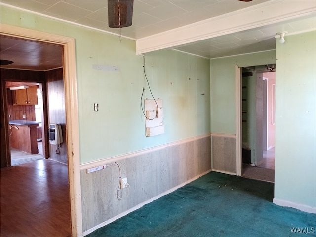 spare room featuring wood walls, carpet floors, ornamental molding, and heating unit