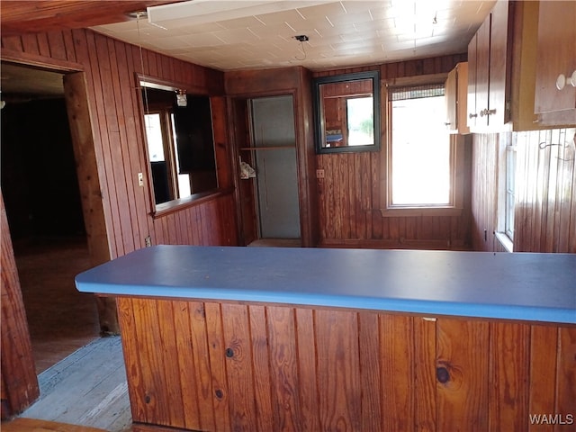 kitchen with kitchen peninsula, light hardwood / wood-style flooring, and wooden walls