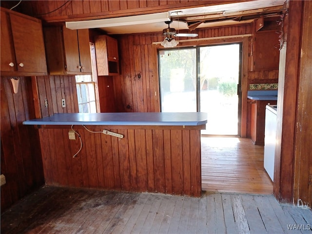 kitchen featuring kitchen peninsula, wood walls, hardwood / wood-style floors, and ceiling fan