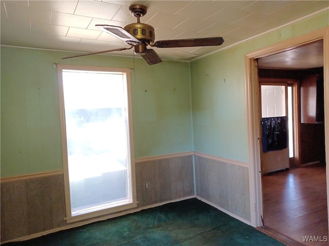 spare room with ceiling fan, wood walls, and dark wood-type flooring