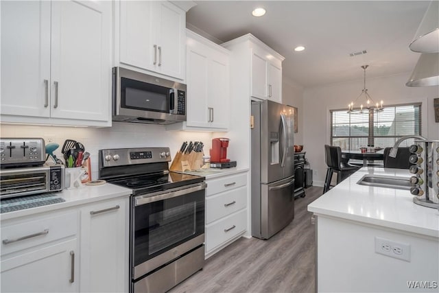 kitchen with white cabinetry, sink, stainless steel appliances, and an inviting chandelier