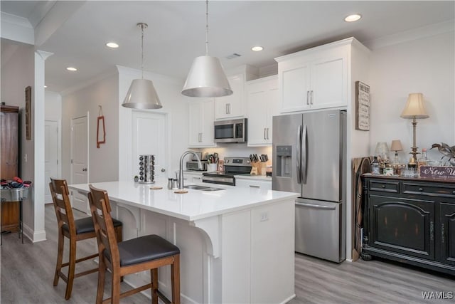 kitchen featuring sink, appliances with stainless steel finishes, a kitchen island with sink, hanging light fixtures, and white cabinets